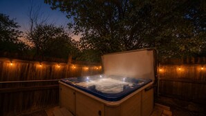 Una vasca idromassaggio con un’area prendisole in legno e una recinzione in legno sullo sfondo.