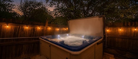 Un bain à remous avec une terrasse en bois et une clôture en bois en arrière-plan.