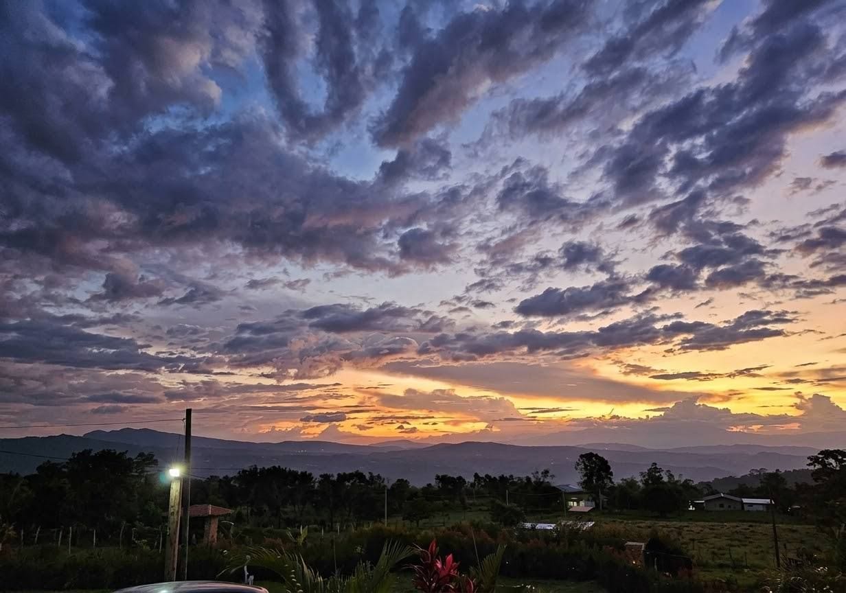 A sunset over a rural landscape with scattered clouds.