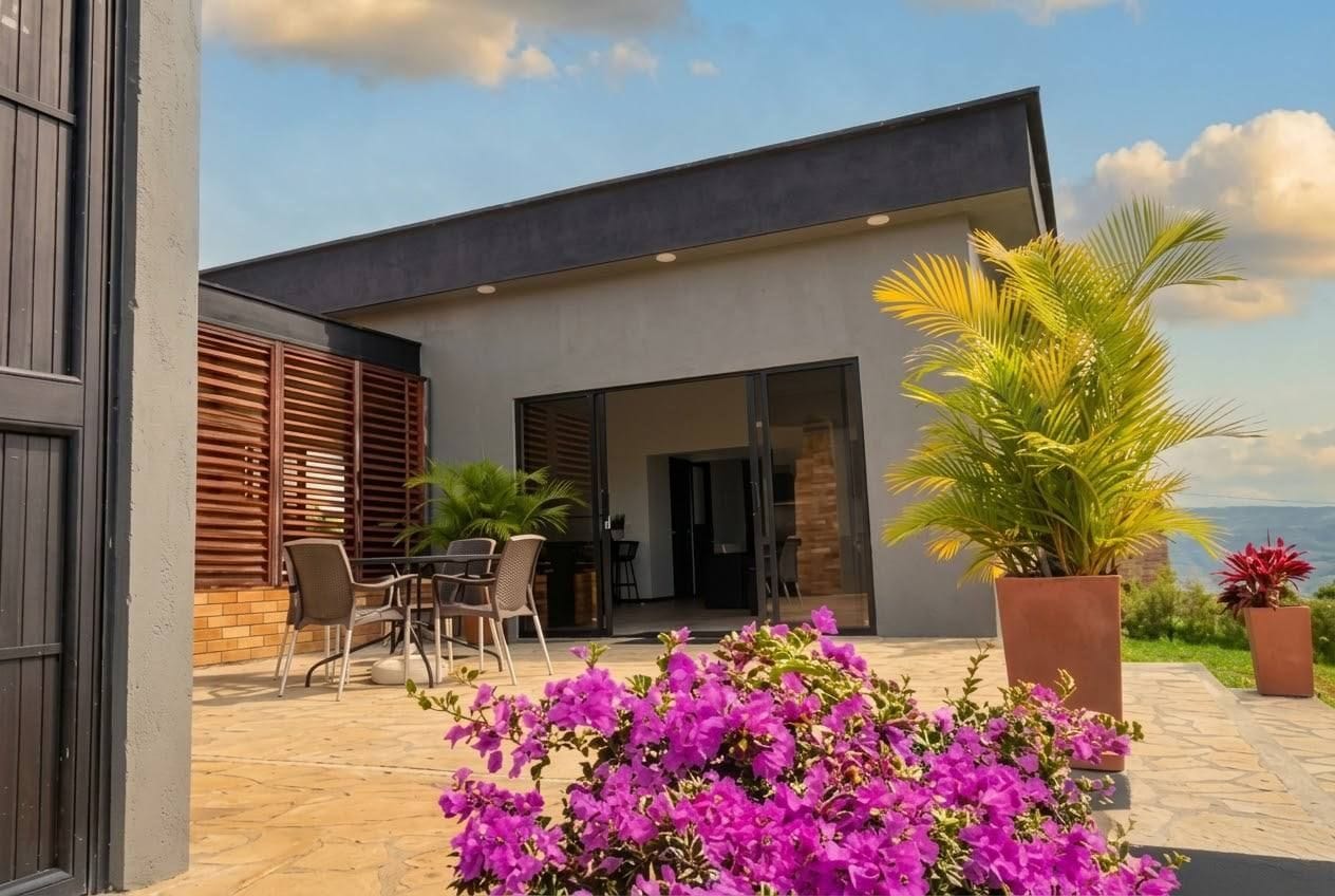 Un edificio moderno con un patio, mobiliario exterior y vistas al paisaje.