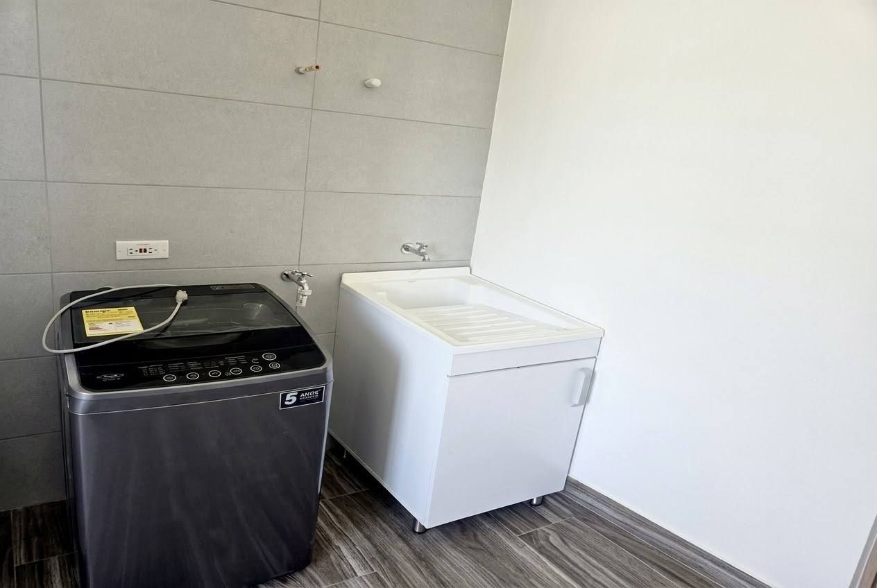 A compact bathroom with a washing machine, a sink, and a toilet.