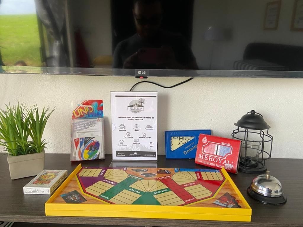 A table with a board game, a plant, a card game, a lantern, and a television.