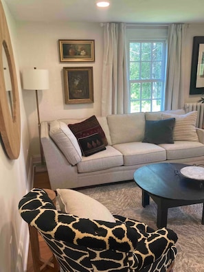 A living room with a sofa, a patterned armchair, a coffee table, and a floor lamp. - 1865 Bennington Farmhouse: Mountain, Monument & Meadow views & Charm (Bennington)