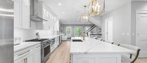 A modern kitchen with white cabinetry, stainless steel appliances, and a central island.