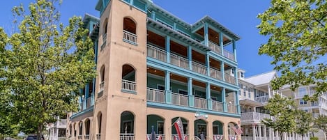 Un edificio de varios pisos con una torre de reloj, balcones y banderas estadounidenses.