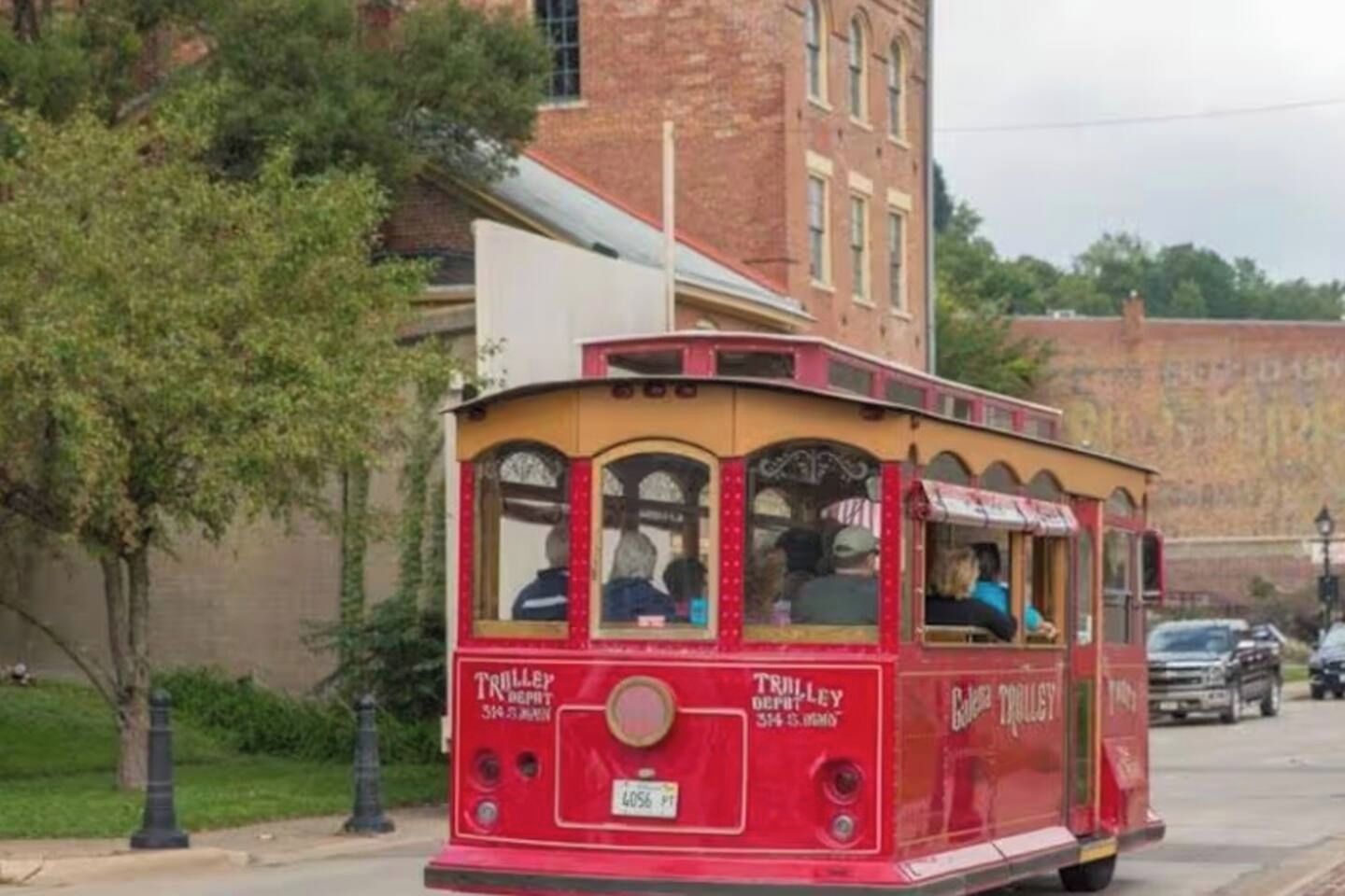 A red trolley with 'TRULLEY' written on the side, parked on a street with a brick building in the background.