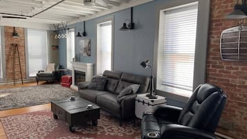 Una sala de estar moderna con un sofá de cuero, un sillón negro, una mesita de centro y una chimenea.