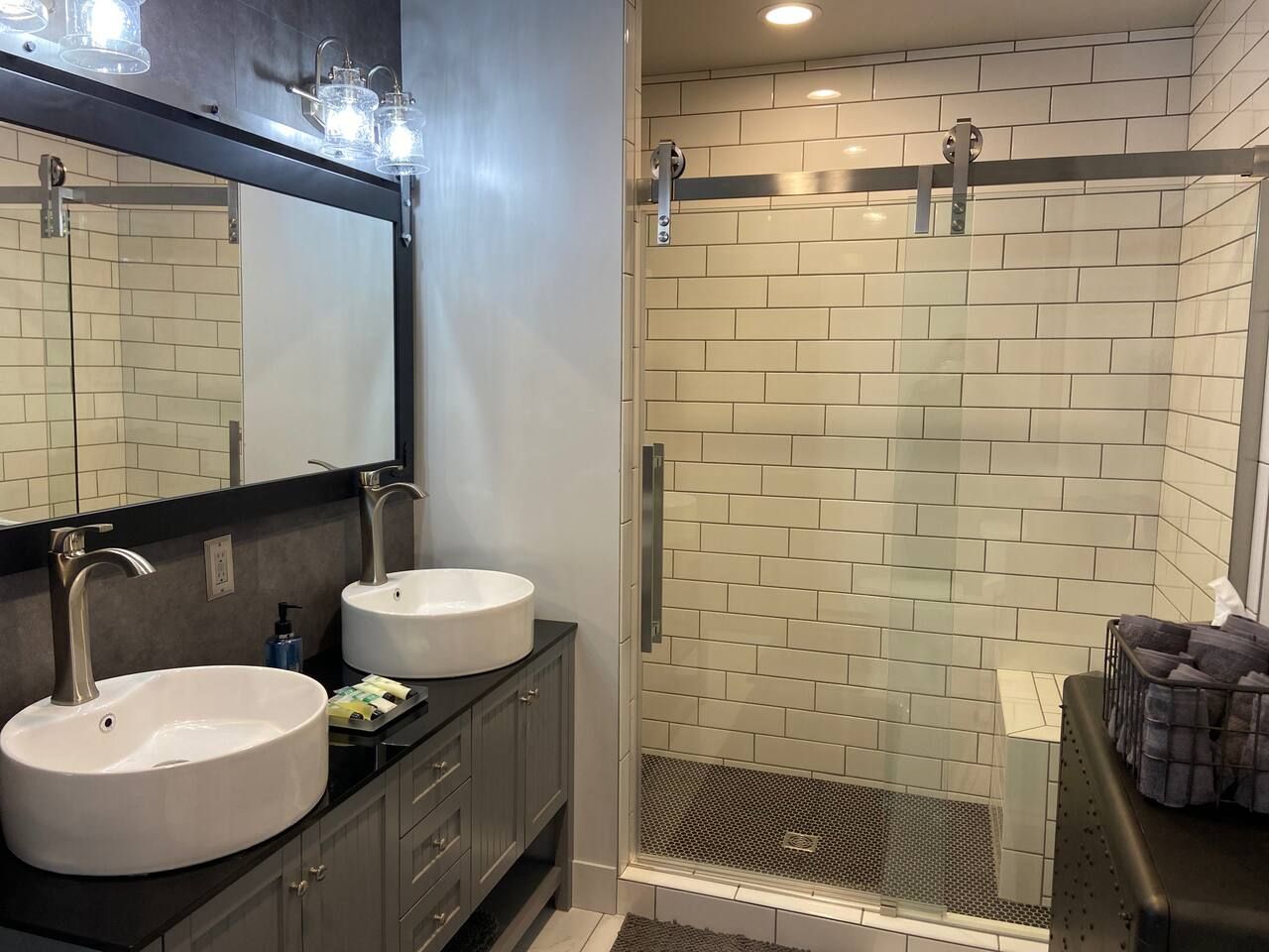 A bathroom with two sinks, a mirror, and a shower area with a glass door.
