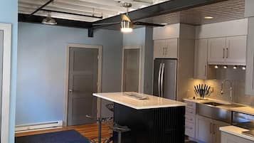 Una cocina compacta con una isla central, electrodomésticos de acero inoxidable y un suelo estampado.