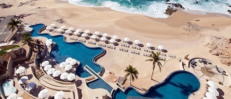 Un complexe hôtelier doté de plusieurs piscines, de chaises longues et d’un accès à la plage.