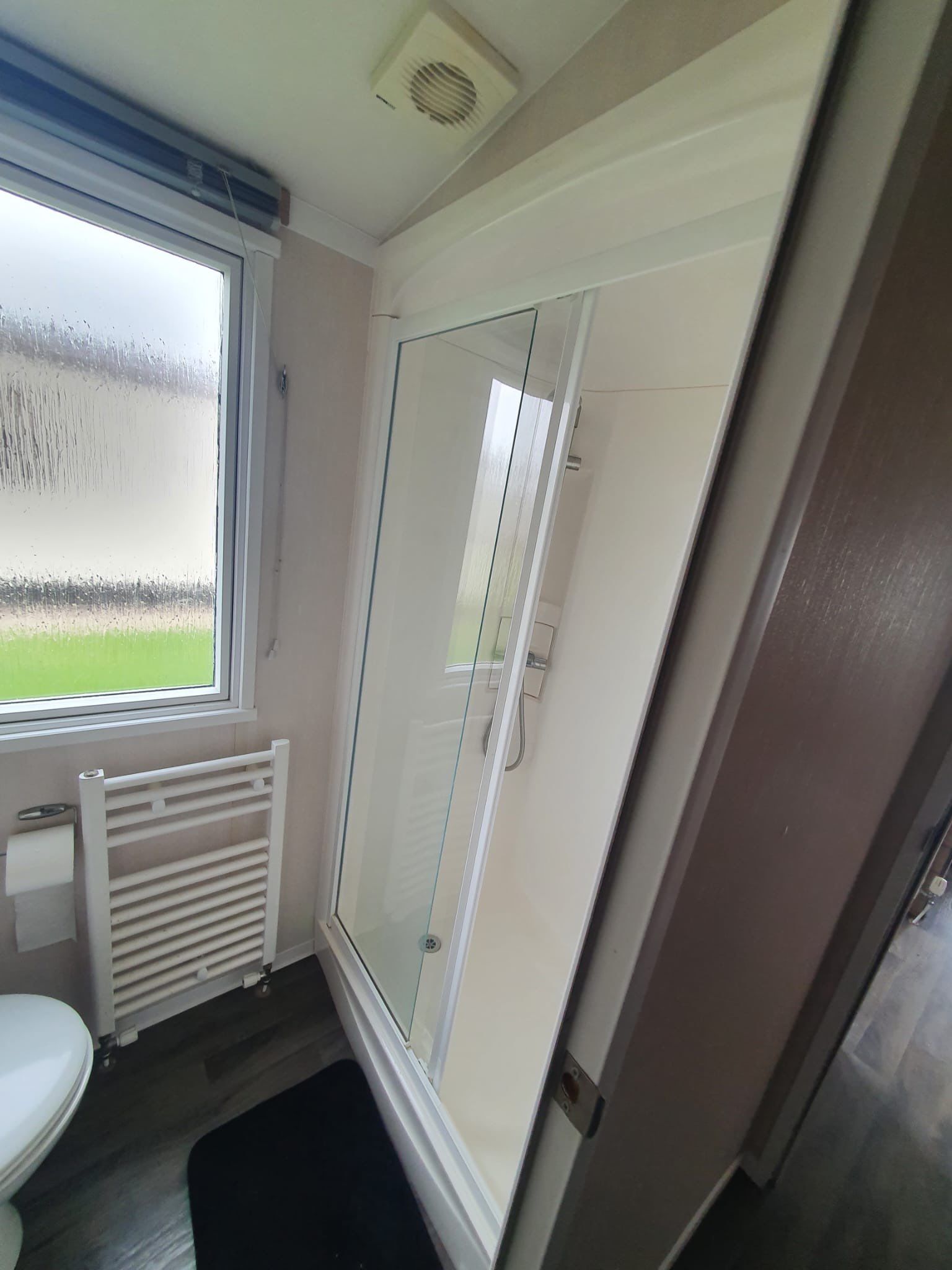 Une salle de bain avec une douche à parois de verre, des toilettes et un radiateur.