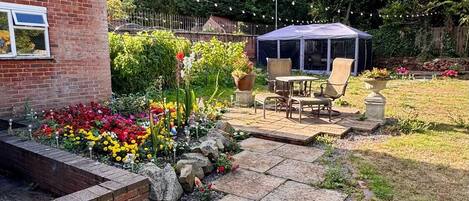 A brick house with a garden patio, a table with chairs, and a blue tent.
