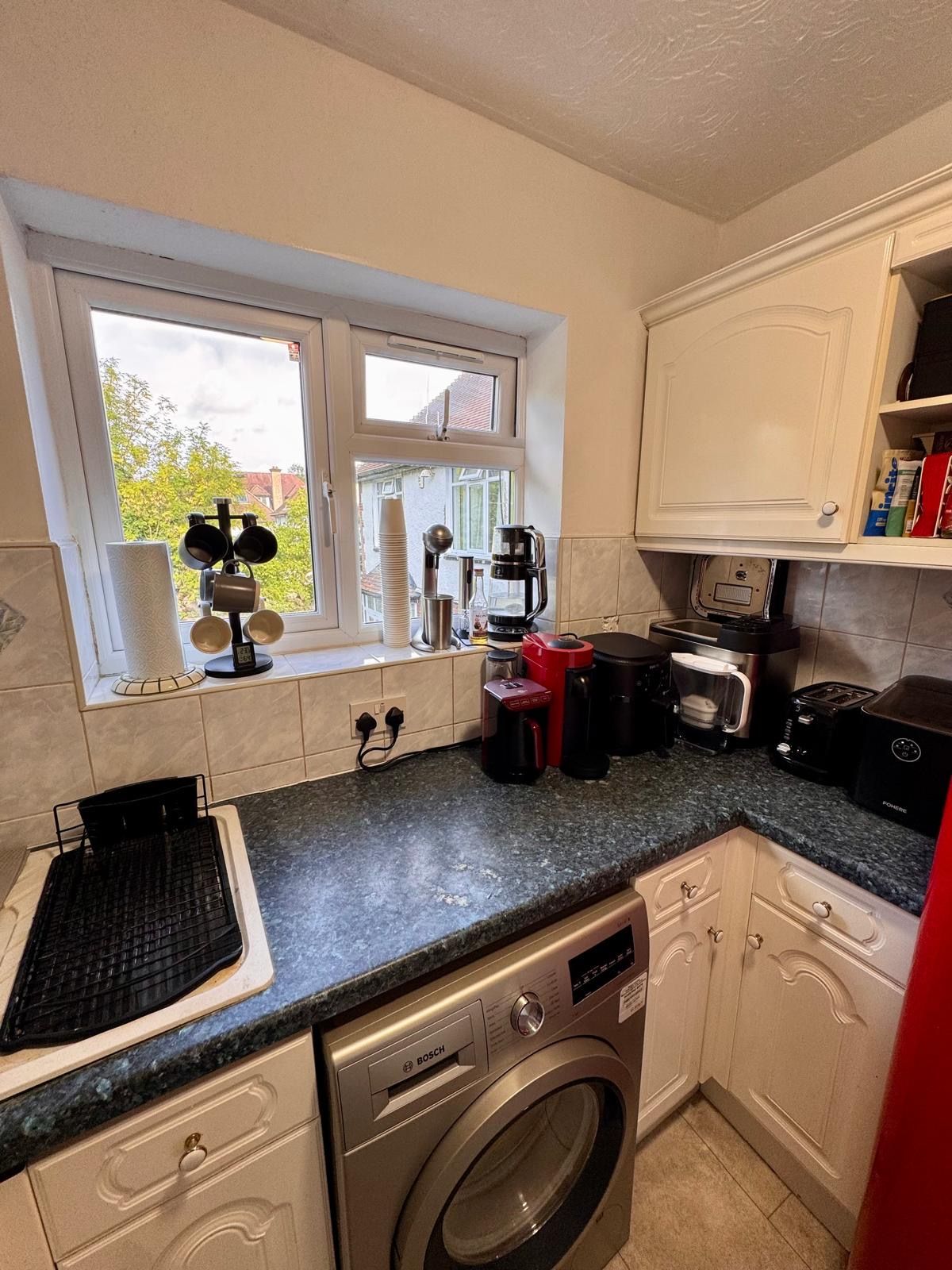 A compact kitchen with a washing machine, a coffee maker, and a toaster.