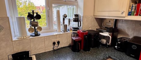 Una cocina compacta con lavadora, cafetera y tostadora.