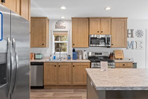Una cocina moderna con armarios de madera, electrodomésticos de acero inoxidable, microondas integrado y encimera de granito.
