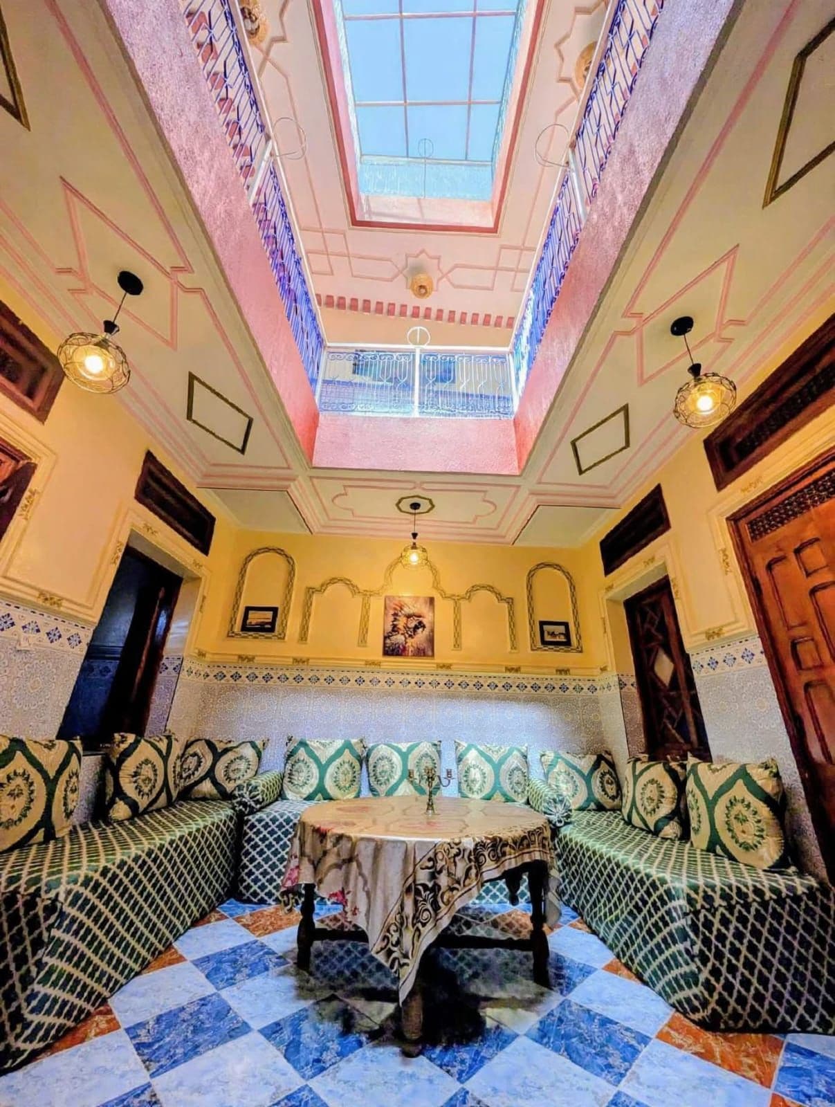 A room with a high ceiling, a skylight, a patterned floor, and a seating area with a table.