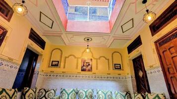 A room with a high ceiling, a skylight, a patterned floor, and a seating area with a table.