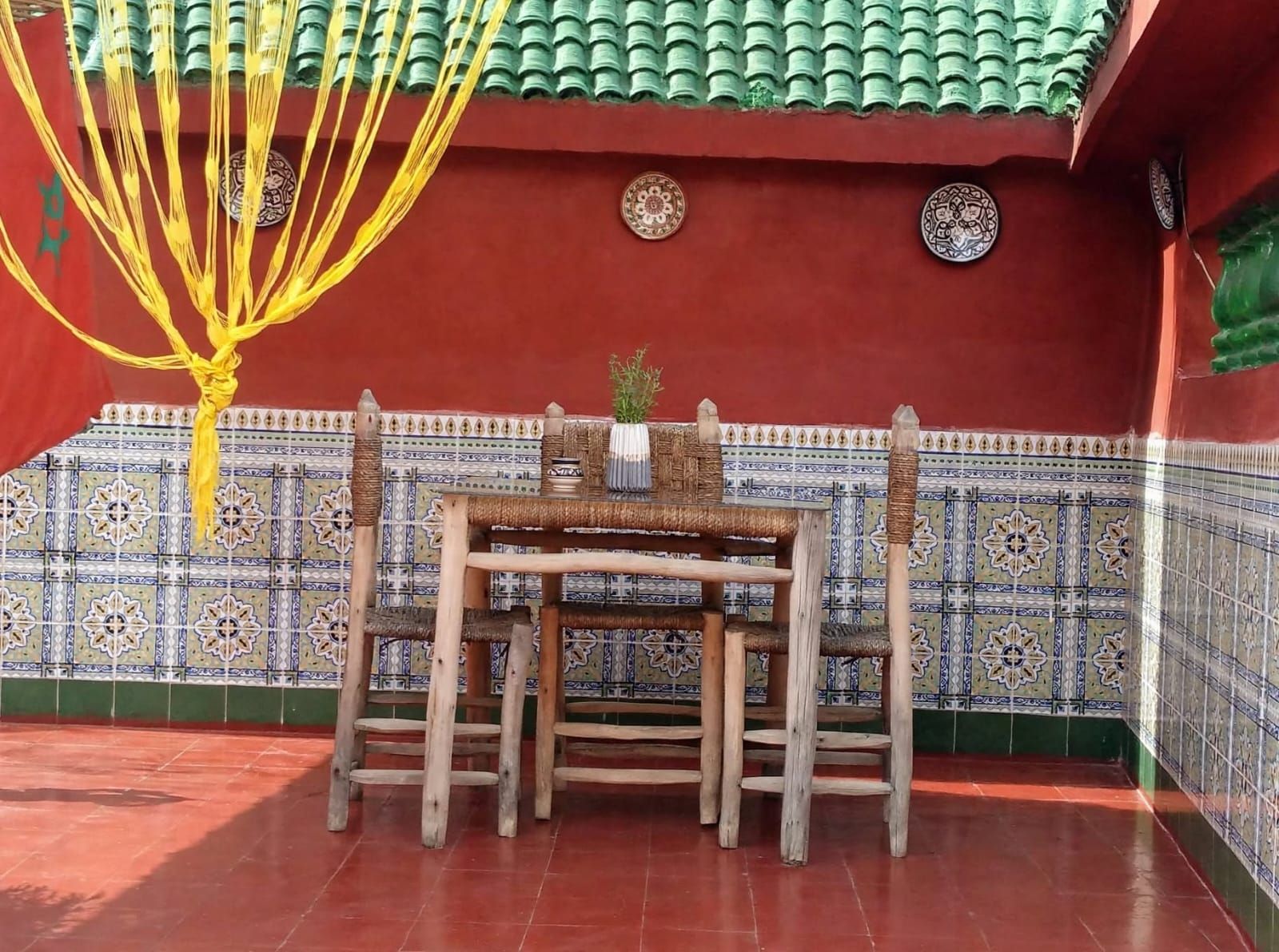 A traditional room with a tiled wall, a wooden table with chairs, and a hanging yellow rope decoration.