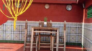 A traditional room with a tiled wall, a wooden table with chairs, and a hanging yellow rope decoration.