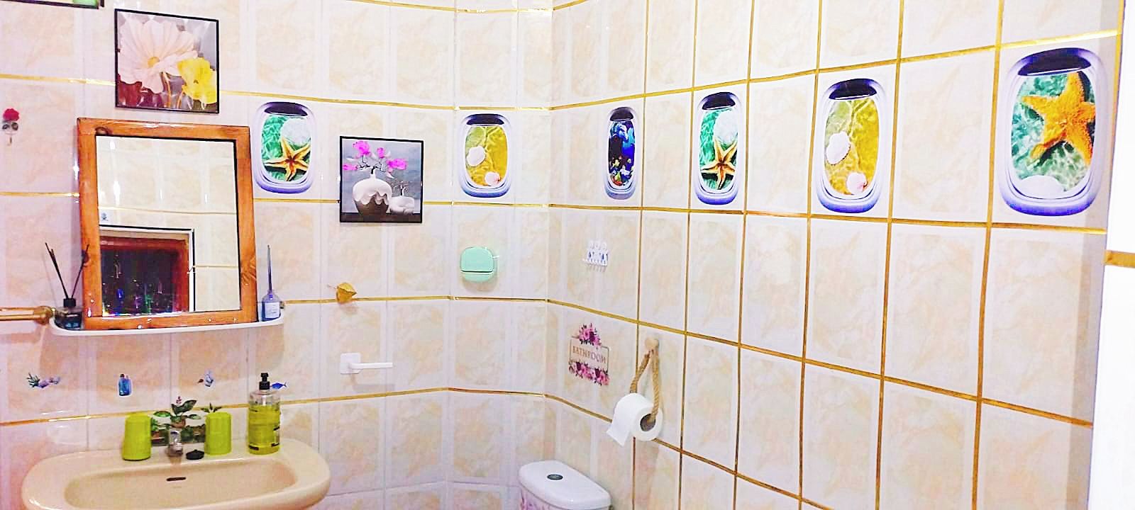 Een badkamer met een wastafel, spiegel, toilet en decoratieve tegels.