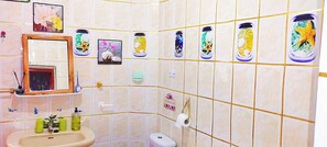 Een badkamer met een wastafel, spiegel, toilet en decoratieve tegels.