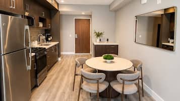 Una cocina moderna con electrodomésticos de acero inoxidable, un comedor con mesa y sillas redondas, y un espejo grande en la pared.