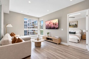 Ein modernes Wohnzimmer mit einer Couch, einem Couchtisch und einem an der Wand befestigten Fernseher.