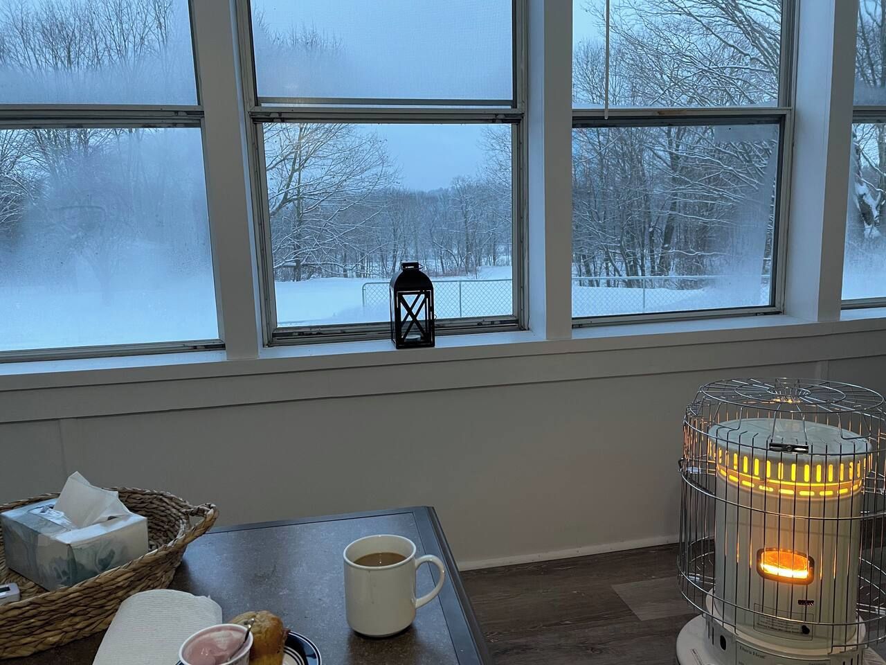 Une pièce chaleureuse avec une table, une tasse, un panier et un radiateur.