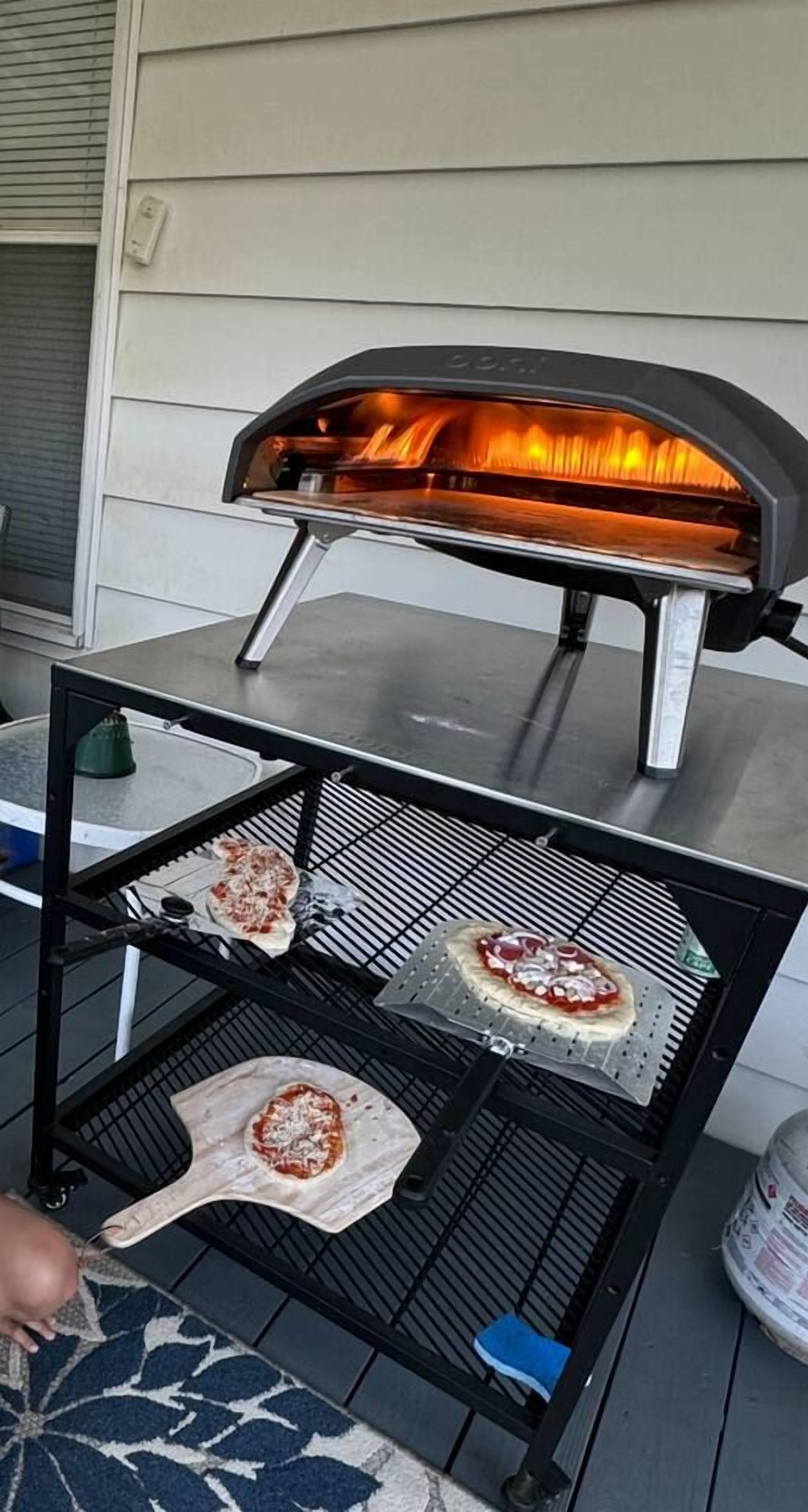 A pizza oven with two pizzas on a rack, one on a wooden board and one on a metal tray.