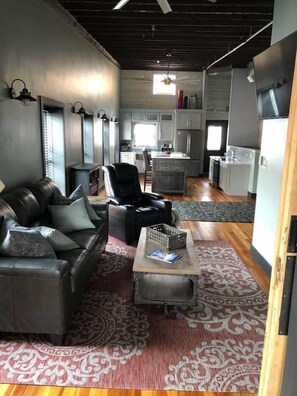 A modern interior with a leather sofa, a dining area, and a kitchen.