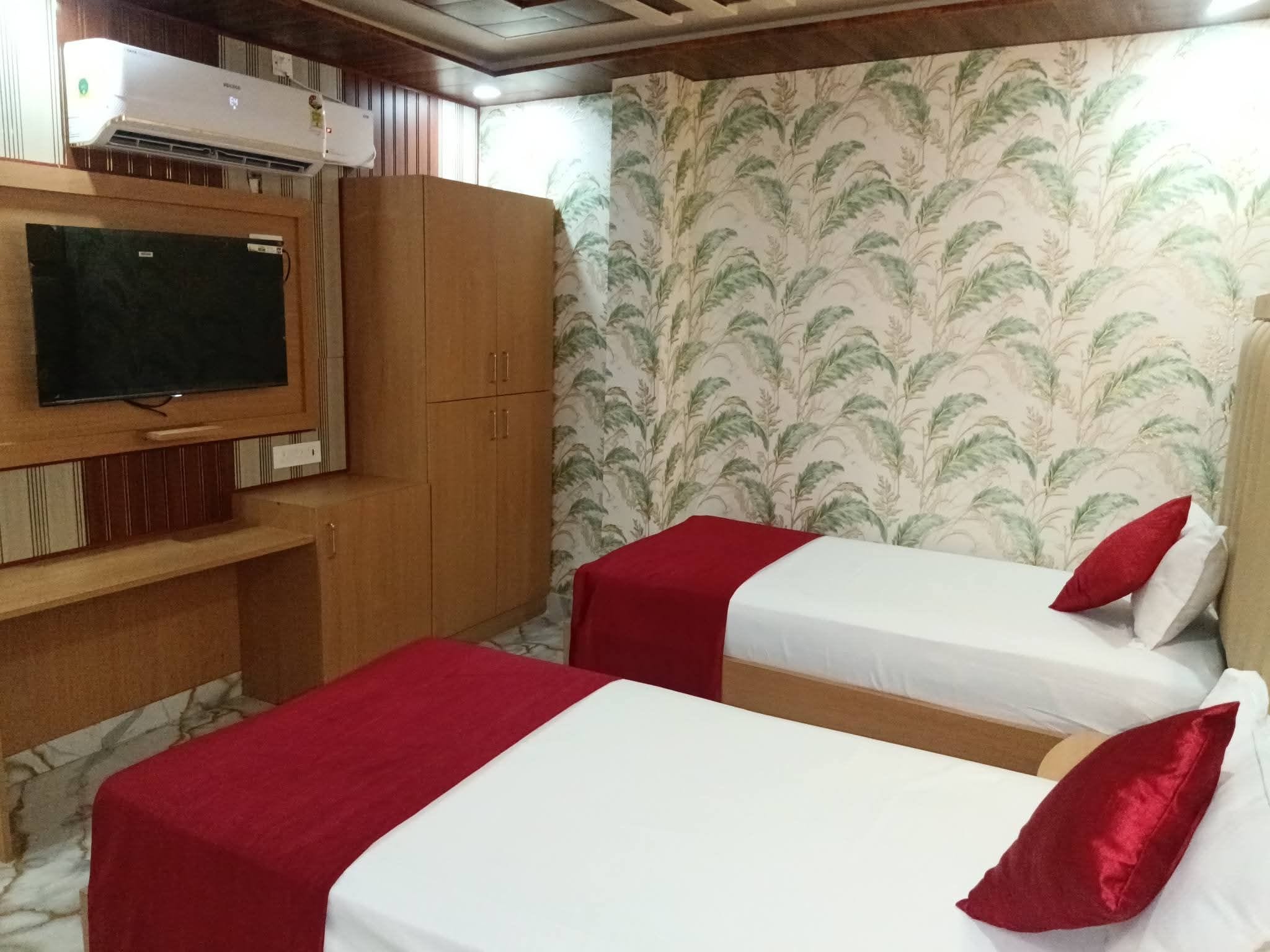 Ein Zimmer mit zwei Betten, einem Fernseher und einem Kleiderschrank.