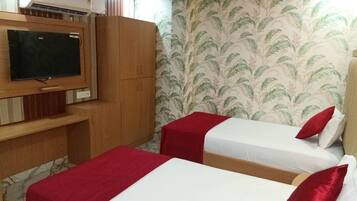 Ein Zimmer mit zwei Betten, einem Fernseher und einem Kleiderschrank.