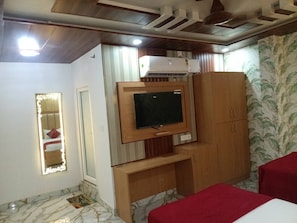 Una habitación de hotel con una cama, televisor, armario y un espejo decorativo.