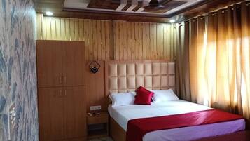 A hotel room with a bed, a wardrobe, a nightstand, and a ceiling with a geometric design.