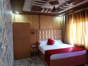 Une chambre d’hôtel comprenant un lit, une armoire, une table de chevet et un plafond orné de motifs géométriques.