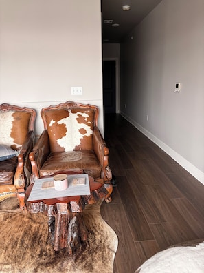 A room with a brown leather sofa, a wooden coffee table, and a fur rug.