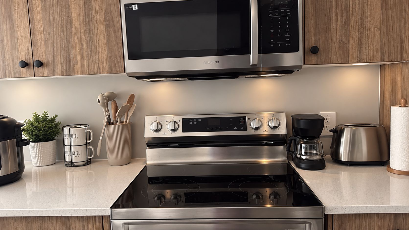A modern kitchen with a stainless steel microwave, oven, and coffee maker.