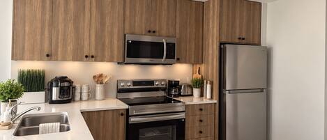 Une cuisine moderne avec des meubles en bois, des appareils électroménagers en acier inoxydable et un four à micro-ondes encastré.