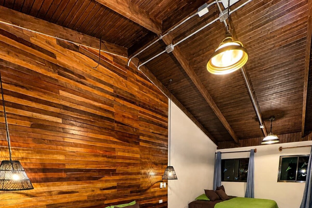 A room with two beds, wooden walls, and a sloped ceiling.