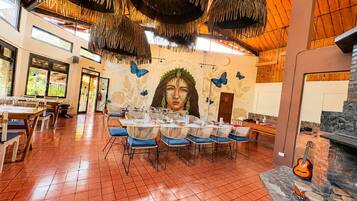 A restaurant with a mural, wooden ceiling, and a stone fireplace.