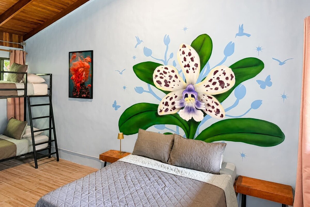 A bedroom with a bunk bed, a large orchid mural, and a painting on the wall.