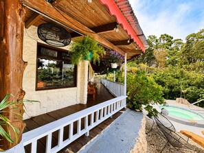 A wooden building with a balcony, a pool, and lush greenery.