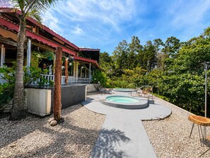 A pool area with a circular hot tub, surrounded by a deck and a covered seating area.