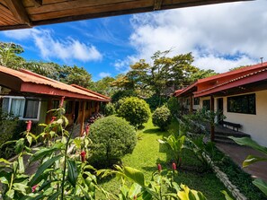 A courtyard with two buildings, a well-maintained lawn, and various plants.