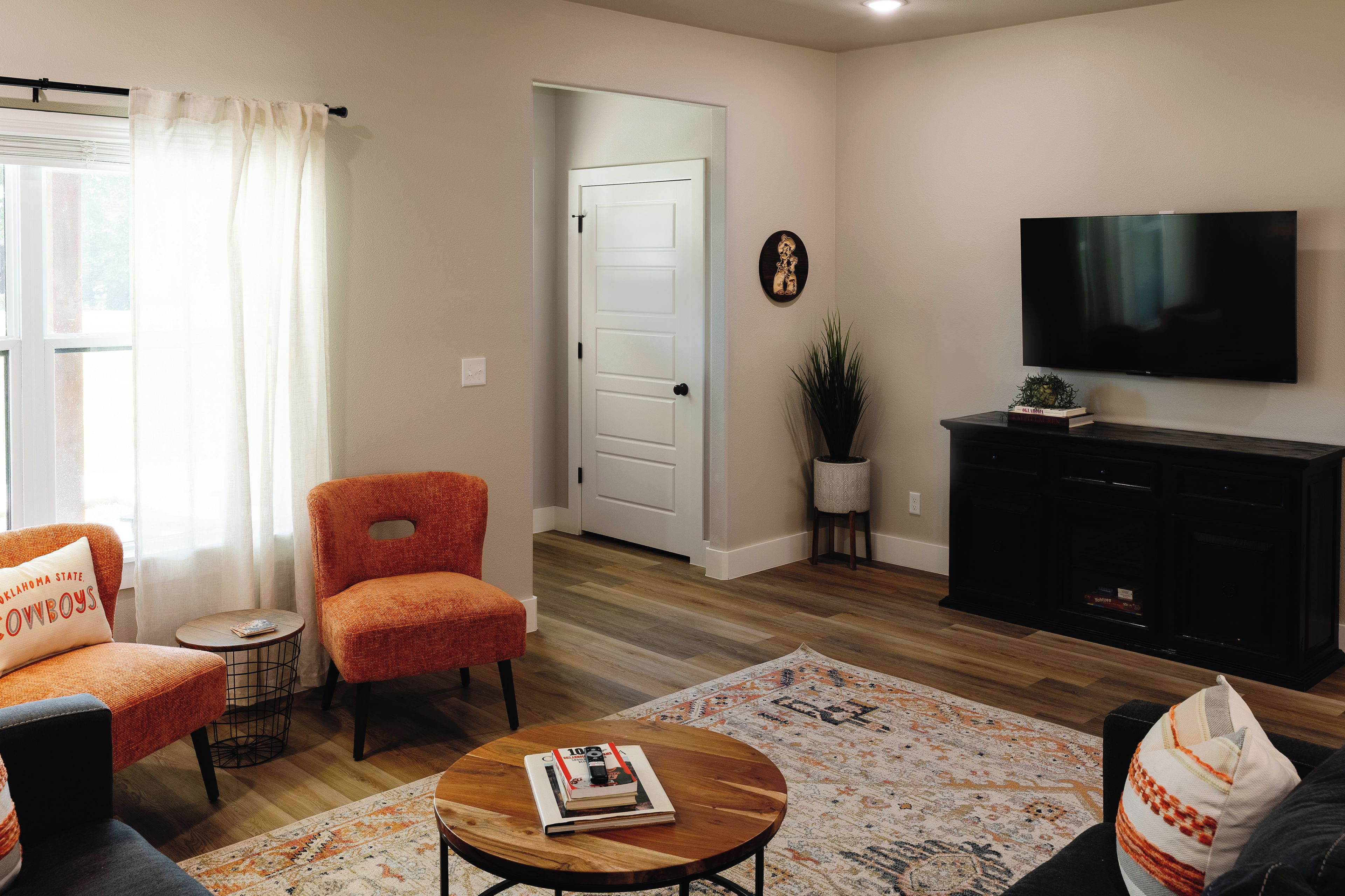 A living room with a sofa, armchair, coffee table, TV, and a door.