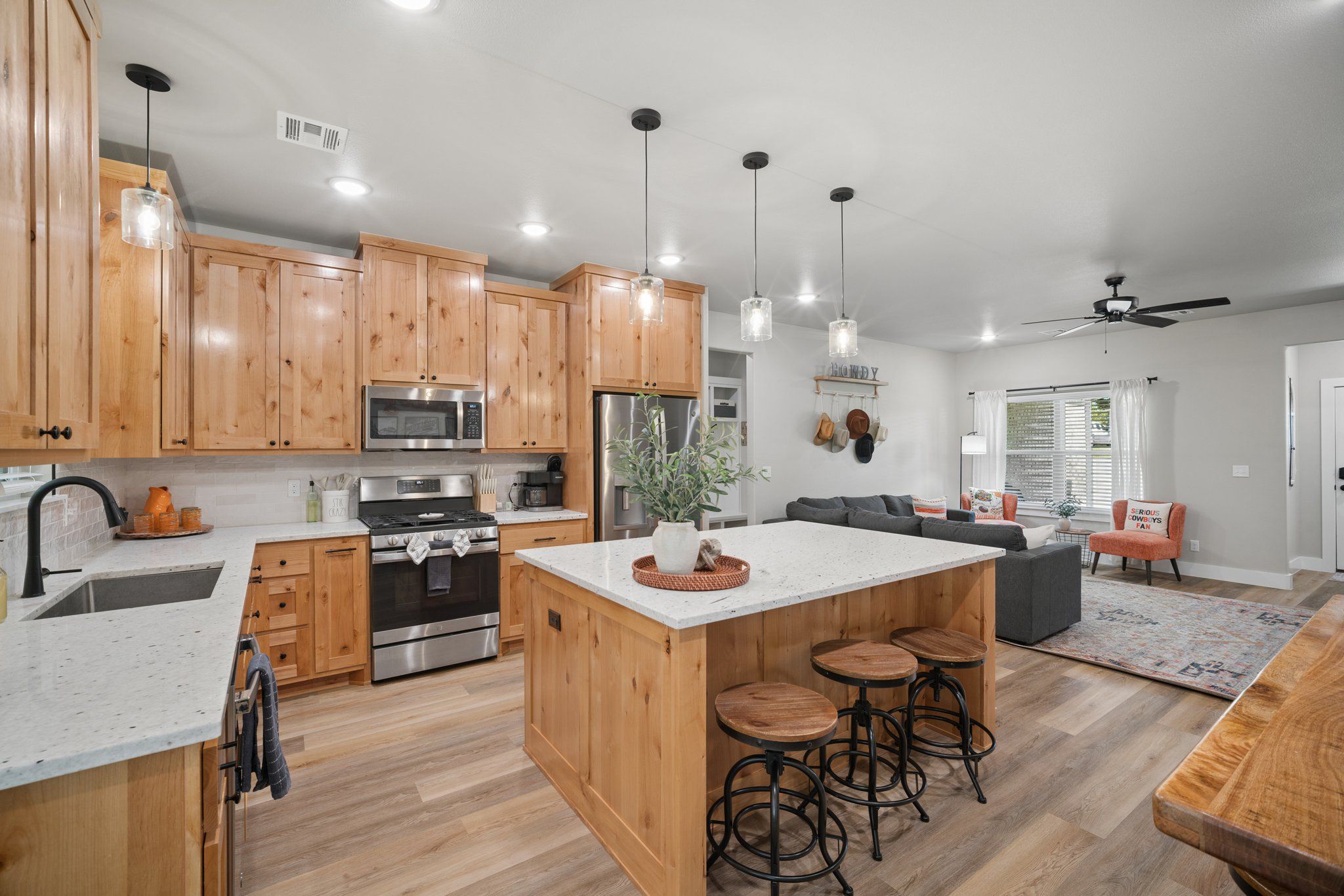 A modern kitchen with wooden cabinets, stainless steel appliances, and a central island with stools.