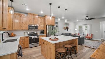 A modern kitchen with wooden cabinets, stainless steel appliances, and a central island with stools.