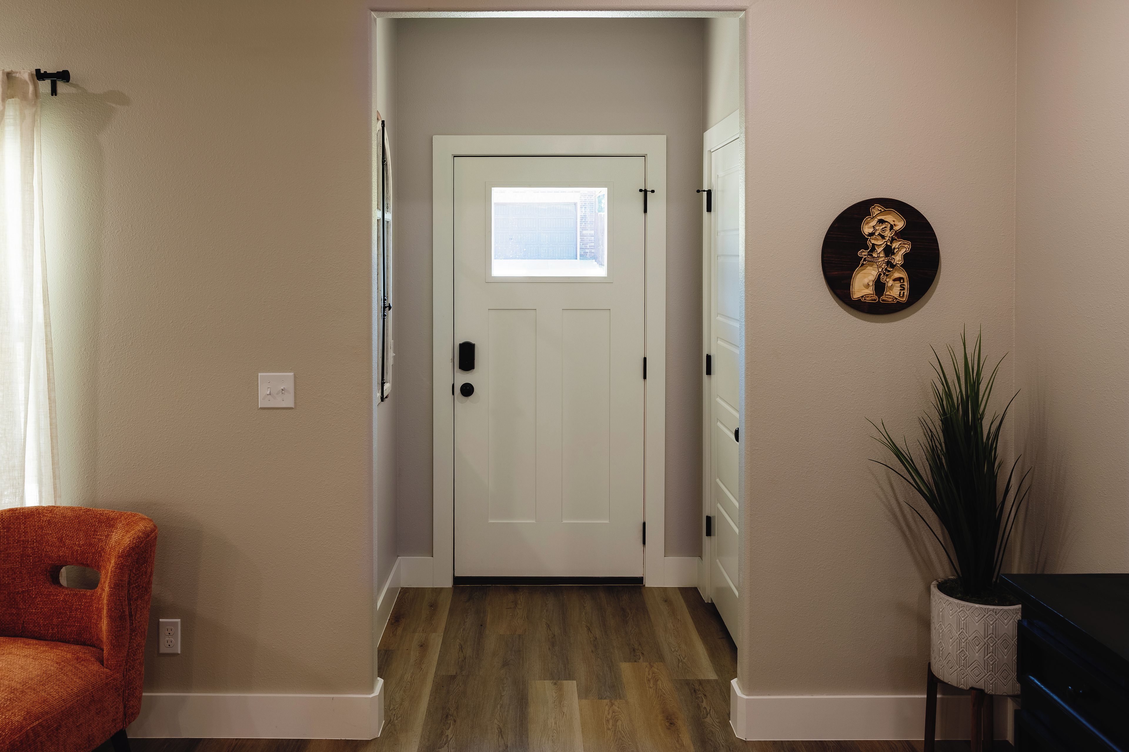 A hallway with a white door, a small window, and a wall-mounted decoration.