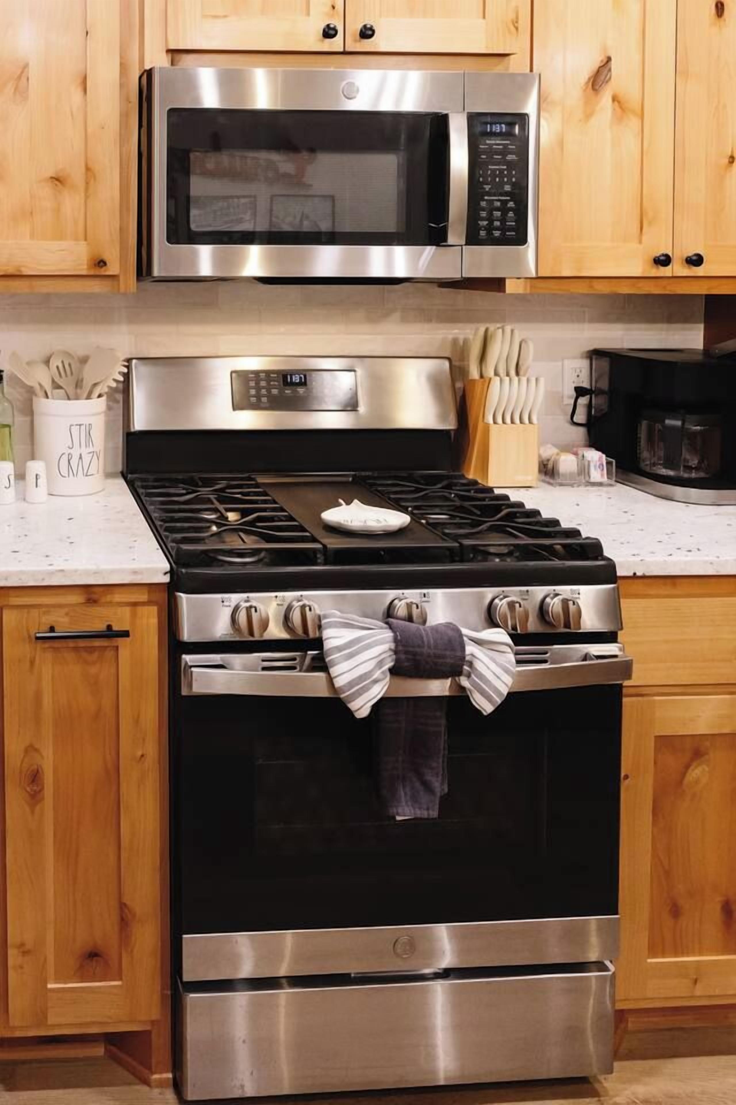 A kitchen with a stainless steel stove, a microwave above it, and wooden cabinets.