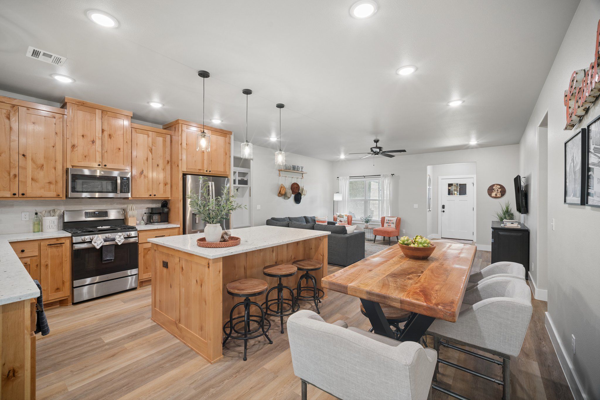 A modern kitchen with wooden cabinets, stainless steel appliances, and a central island with stools.